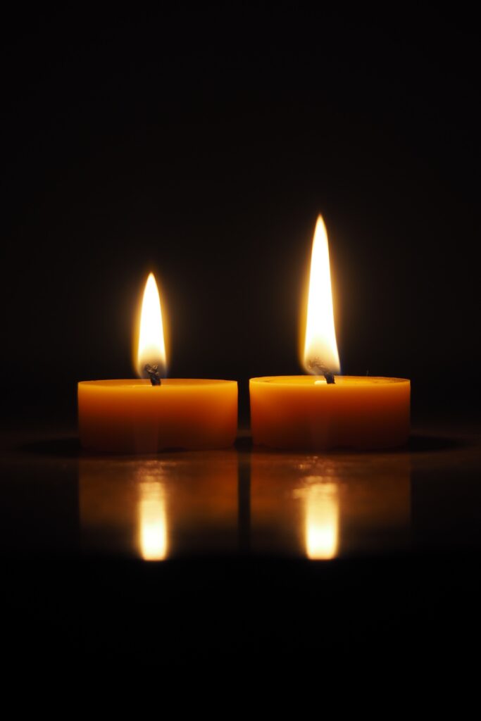 dwie palące się świeczki tealight z wosku pszczelego